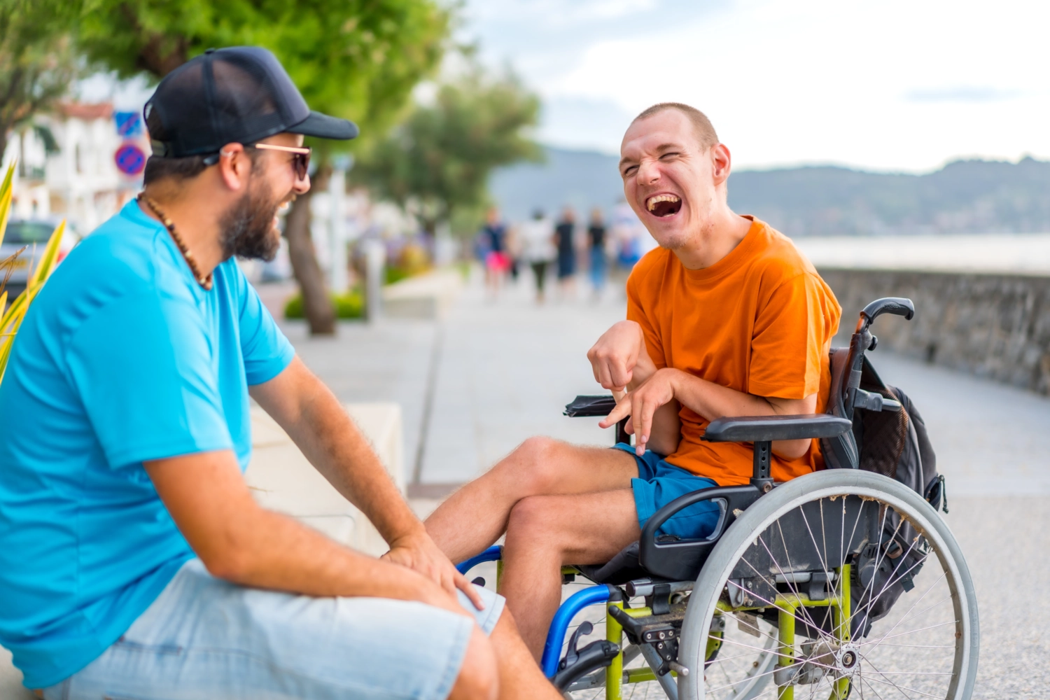 Begleitperson spricht lachend mit einem Mann im Rollstuhl